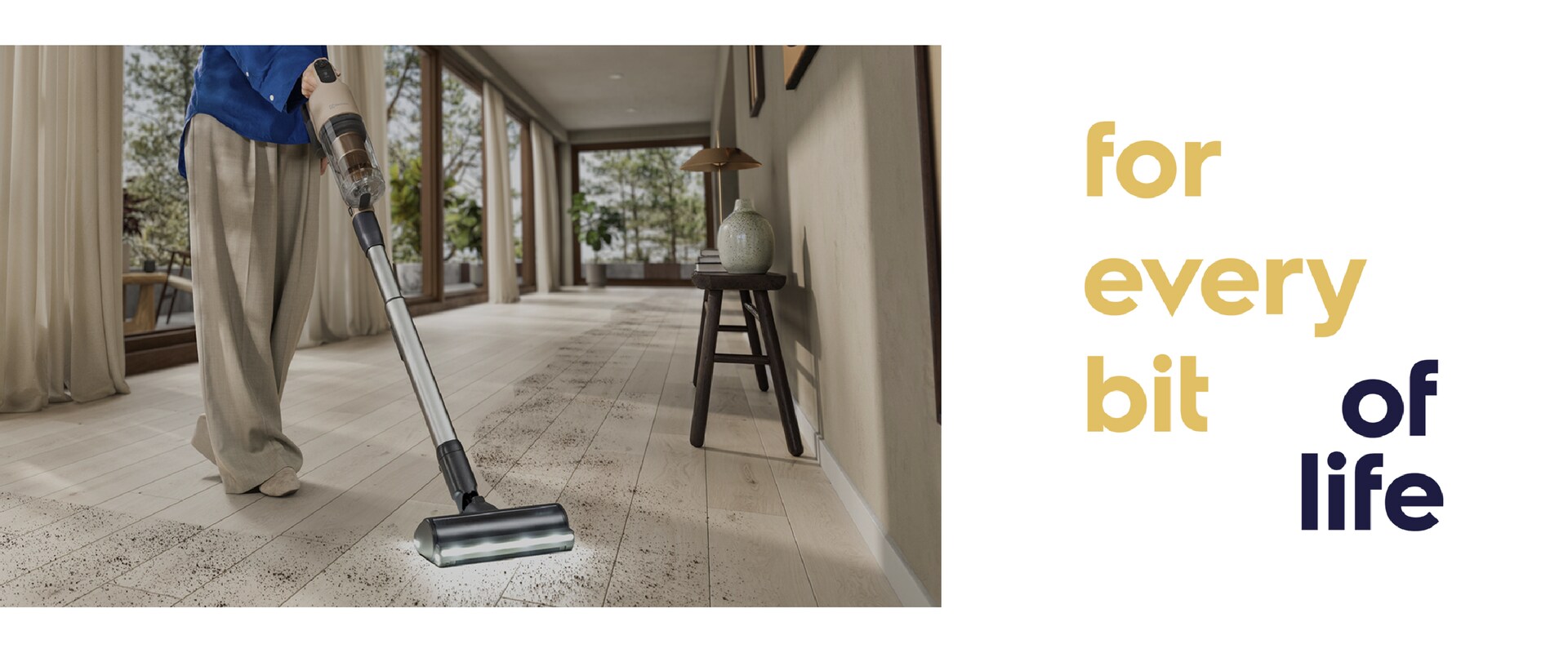 Person cleaning floor with vacuum cleaner with "for every bit of life" text at the right side.