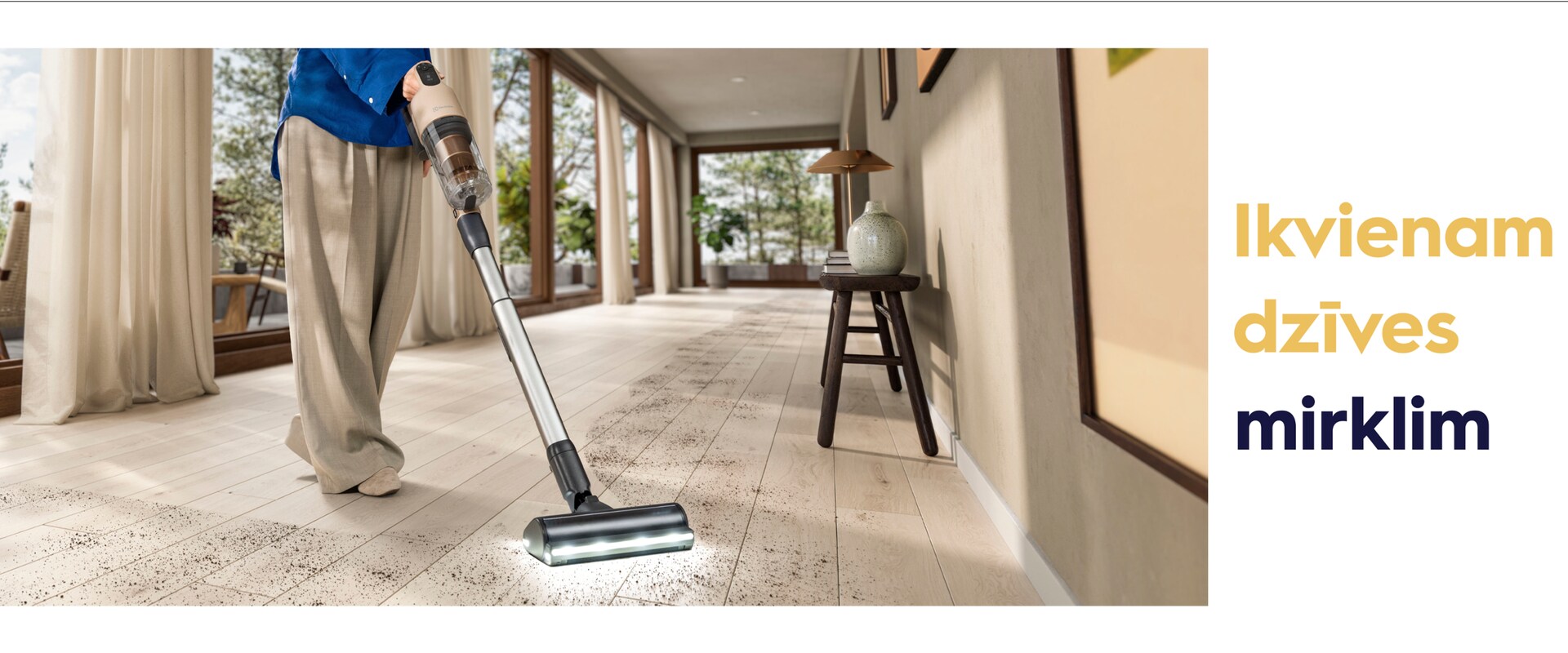 Person cleaning floor with vacuum cleaner with "for every bit of life" text at the right side.